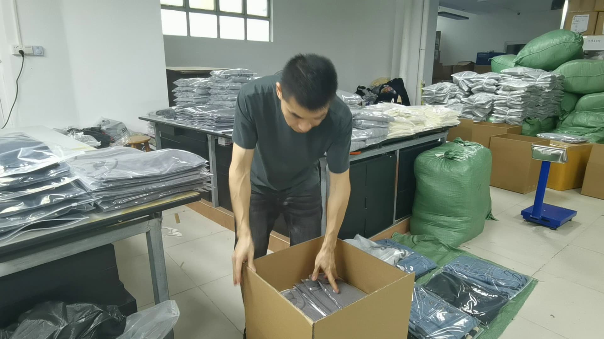 Worker packing polybagged garments into an export carton at Meiting Garments warehouse