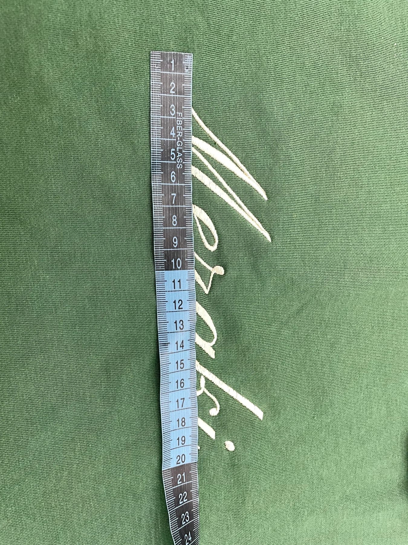 Embroidery placement measurement on green garment fabric