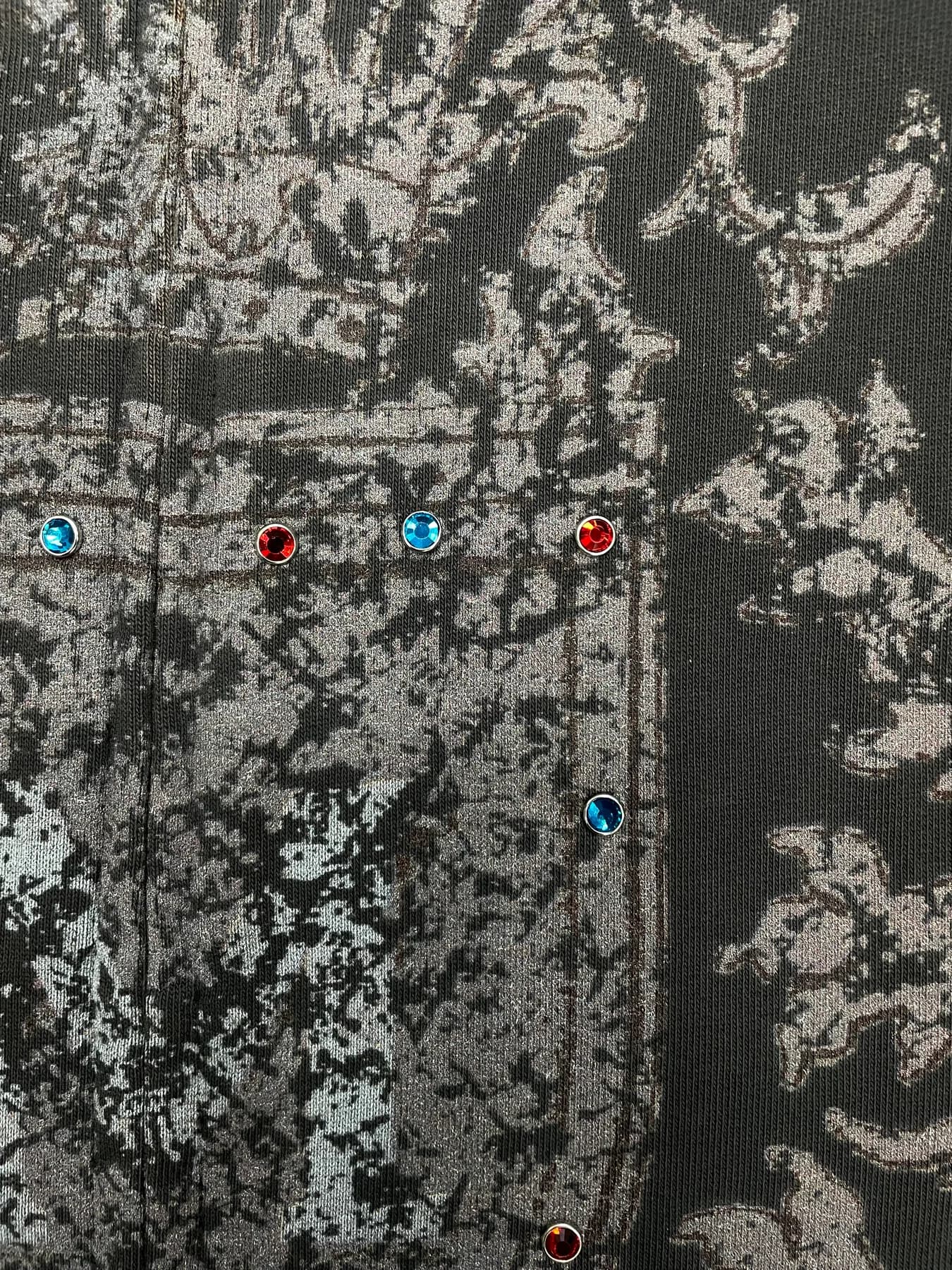 Close-up of a dark graphic garment surface with metallic print and colored stones