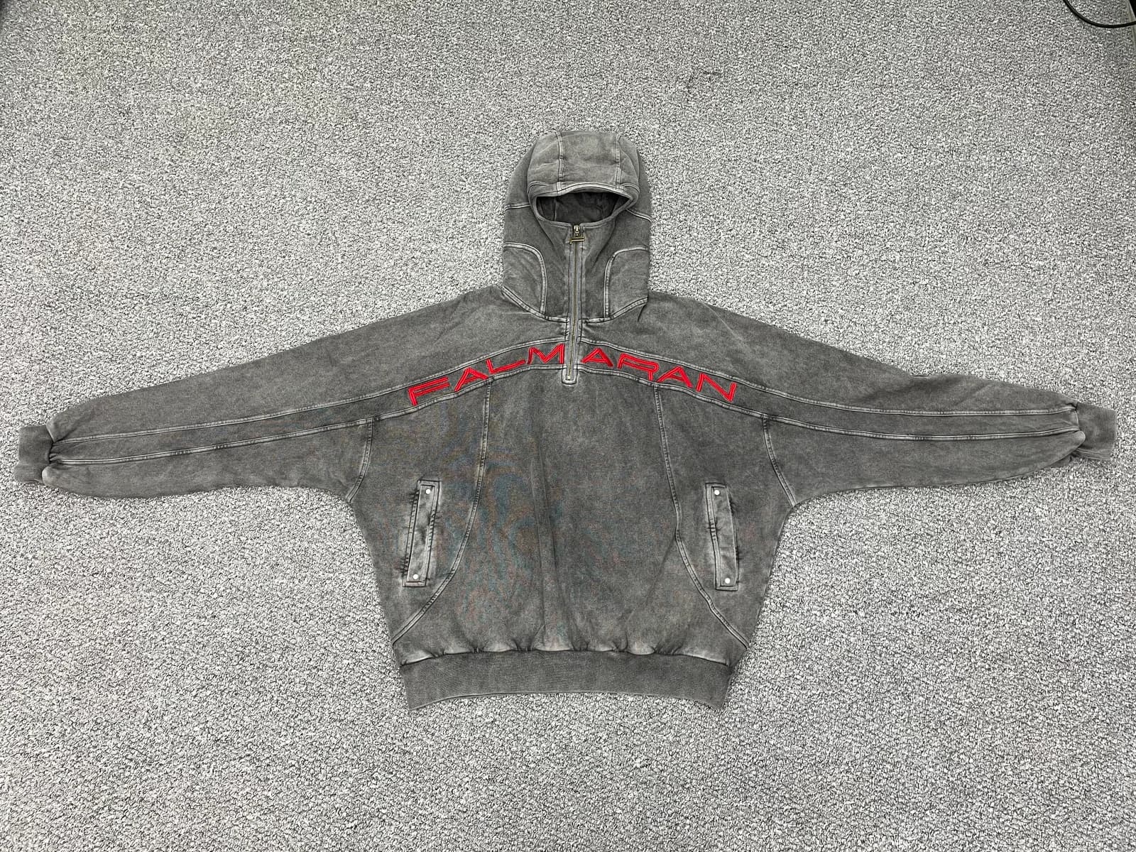 Grey vintage-wash zip hoodie laid flat with panel seams and red embroidery